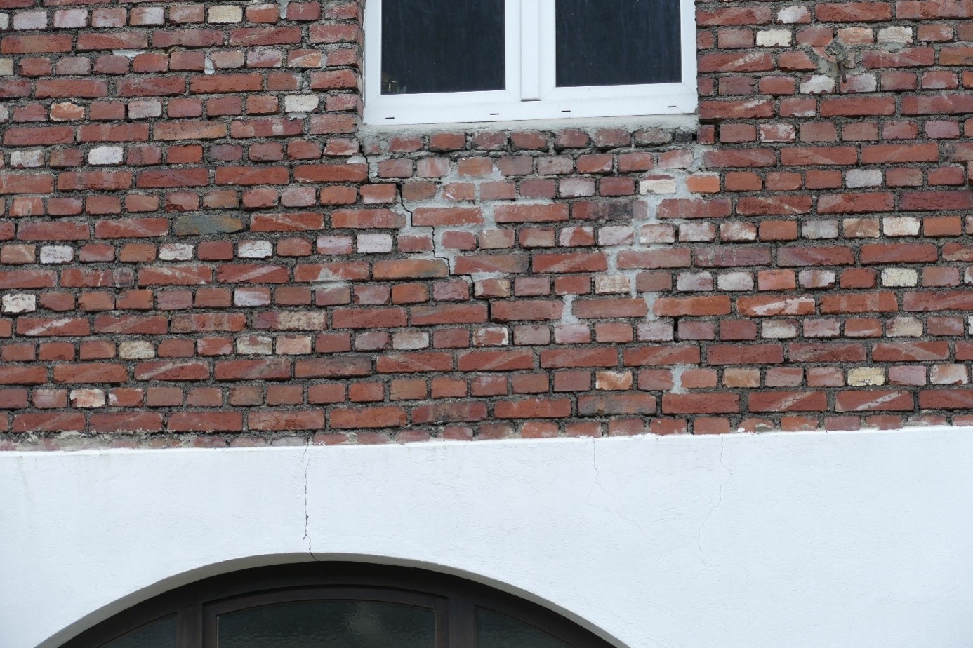 Bauschadengutachten bei treppenfoermigen Rissen im Klinkermauerwerk und Putzriss an einer Hausfassade.