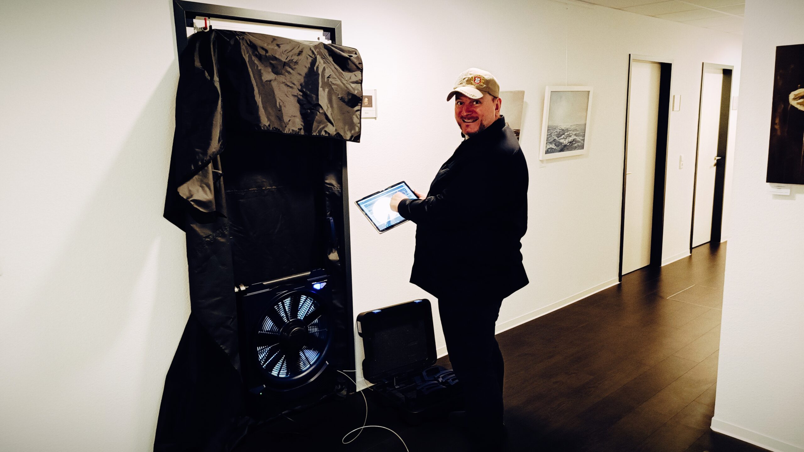 Energieberater steuert den Blower-Door-Test digital über ein Tablet während einer Luftdichtheitsmessung.