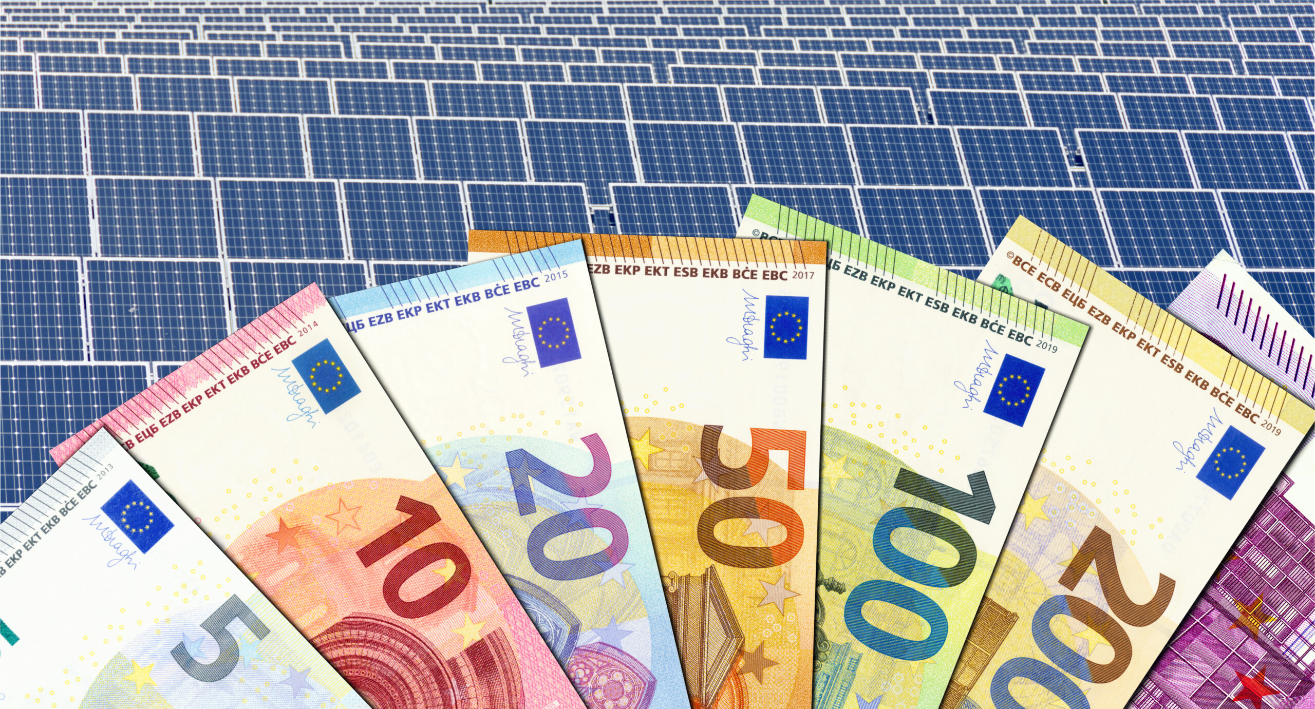 Aufgefächerte Euro-Geldscheine vor einer Solaranlage als Symbol für die Fördermittelberatung Sanierung.
